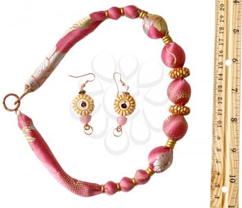 pink silk beads, earrings and wooden rule isolated on white