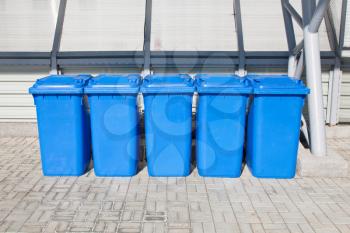 five blue plastic recycling bins outdoor
