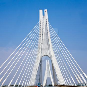 white cable-braced bridge with blue sky background