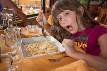 girl eats pasta in italian restaurant in Taormina, Sicily on July, 27, 2011