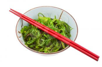 seaweed salad in ceramic bowl with red wooden sticks isolated on white background