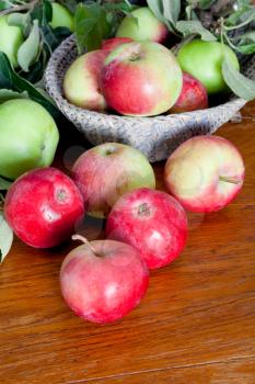 fresh apples with green leaves on wooden table close up