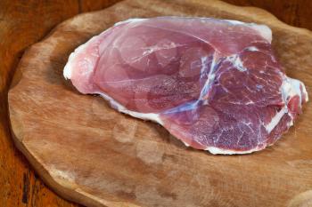 piece of raw pork meat on wooden cutting board