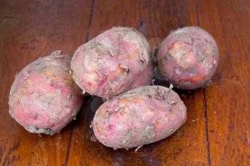 few raw pink potatoes on wooden table