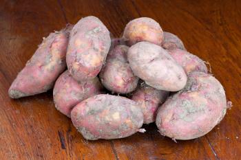 heap of raw pink potatoes on wooden table