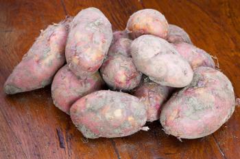 many pink raw potatoes on wooden table