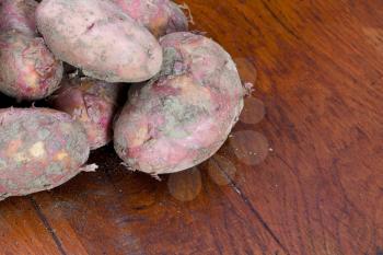 new pink potatoes on wooden table close up