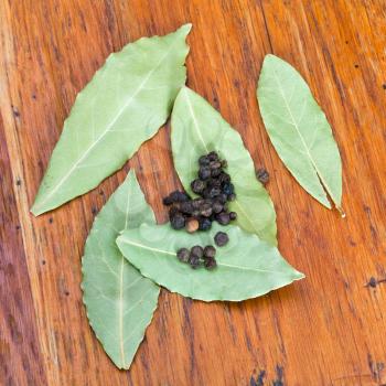 aromatic bay leaves and black peppercorn on wooden table