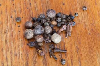 set of spicies from black peppers, allspices, cloves on wooden table