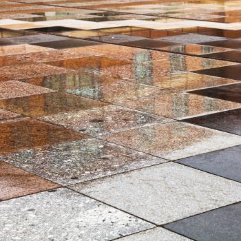 rainy puddles on stone tile of urban square