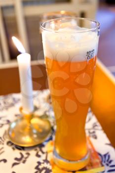 glass of german beer and lit candle on table