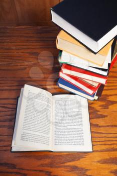 above view of open book with blur font on wooden table near bookcases