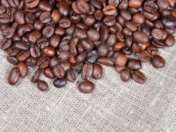 many roasted coffee beans on cloth close up