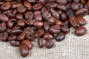 many roasted coffee beans on sacking close up