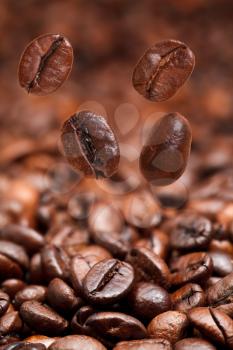 four falling beans and dark roasted coffee beans background with focus foreground