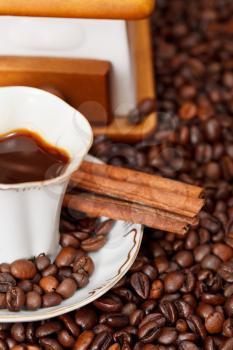 small cup of coffee and roasted coffee beans with retro manual grinder, cinnamon close up