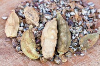 macro view of dried pods and freshly ground cardamon spice on wooden table