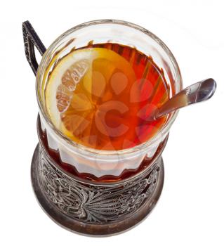 top view of black tea with lemon in vintage glass with spoon isolated on white background