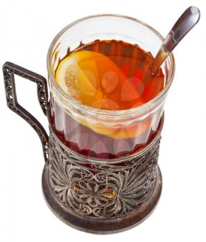 black tea with lemon in vintage glass with spoon and glass holder isolated on white background