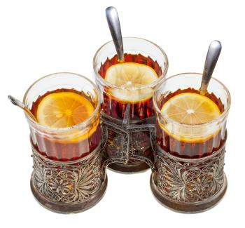 top view of three retro glasses in silver glass holders with black tea and lemon isolated on white background