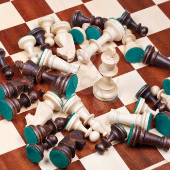 white king and scattered chess pieces on chessboard