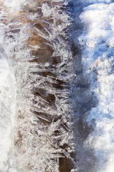 frozen ice crystals under melting snow stream close up