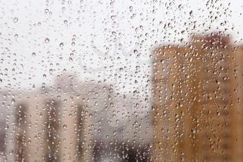 raindrops on glass window with city buildings background
