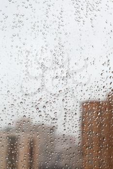 raindrops on glass window with town house background