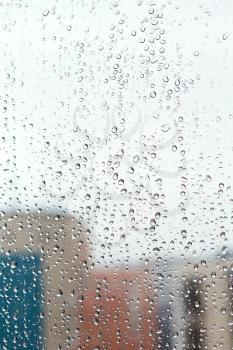 rain drops on glass window with houses background