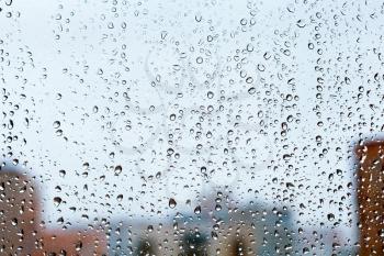raindrops on glass window with blue evening city background