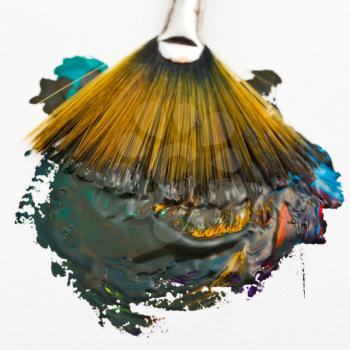 fan paintbrush merges multicolored watercolor paints close up