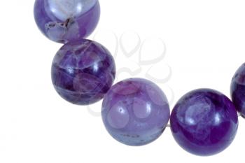 string of round amethyst beads close up isolated on white background