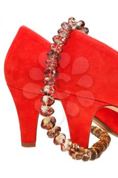 heelpieces of red high heel pumps with necklace isolated on white background