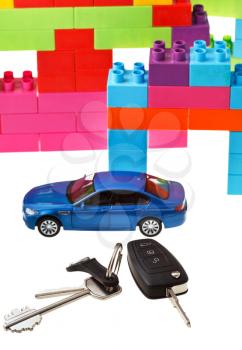 door key, vehicle keys close up, blue model car and plastic block house isolated on white background
