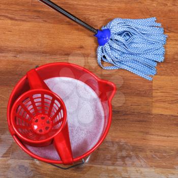 top view of cleaning of wooden floors and red bucket with washing water