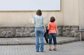 children look at advertising banner on building wall