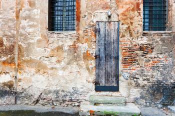 picturesque old wooden door in shabby brick wall of medieval house in Bologna, Italy