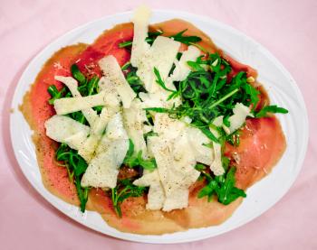 italian carpaccio with parmesan cheese and arugula on white plate
