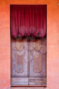 wooden door with red curtain of medieval house in Bologna, Italy