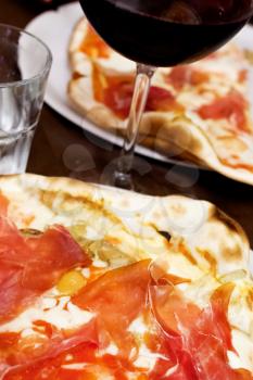 italian pizza with parma ham and glass of red wine in restaurant