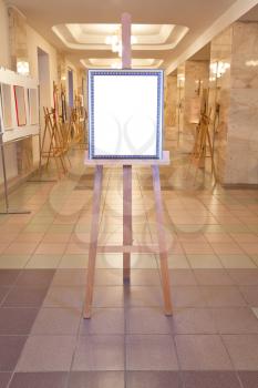 silver picture frame with white cut out canvas on easel in art gallery hall