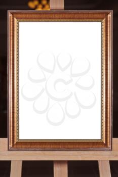 brown wooden picture frame with white cut out canvas on easel