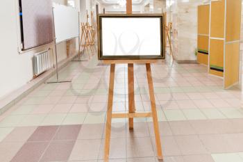 golden wood picture frame with white cut out canvas on easel in art gallery hall