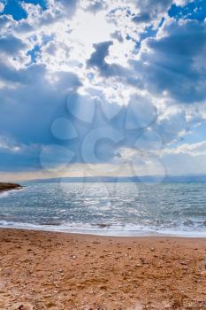sunbeams though dark blue clouds above Dead Sea