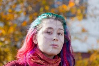 young woman with multicoloured streaks hair outdoor in autumn day
