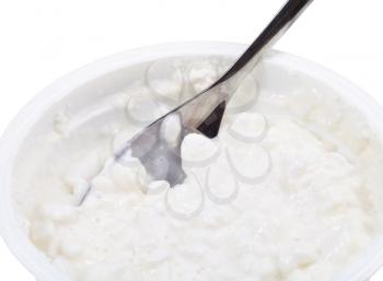 metal spoon in tub of cottage cheese isolated on white background