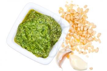 top view on italian pesto with fresh pine nuts and garlic cloves isolated on white background