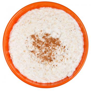 top view on traditional english oat porridge with cinnamon in orange bowl isolated on white background