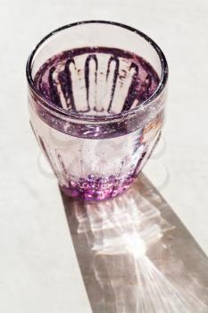 Purple faceted glass with spring water lit by the sun light