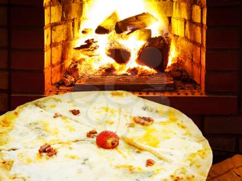 italian pizza quatro formaggi and open fire in wood burning oven
